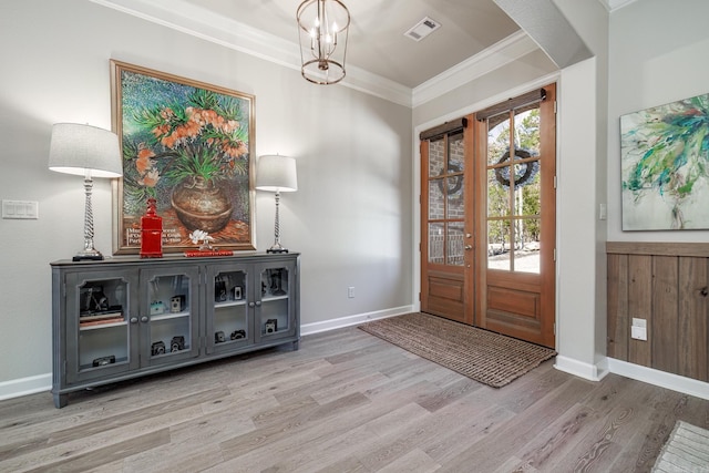 entryway featuring crown molding, visible vents, light wood-style floors, a chandelier, and baseboards