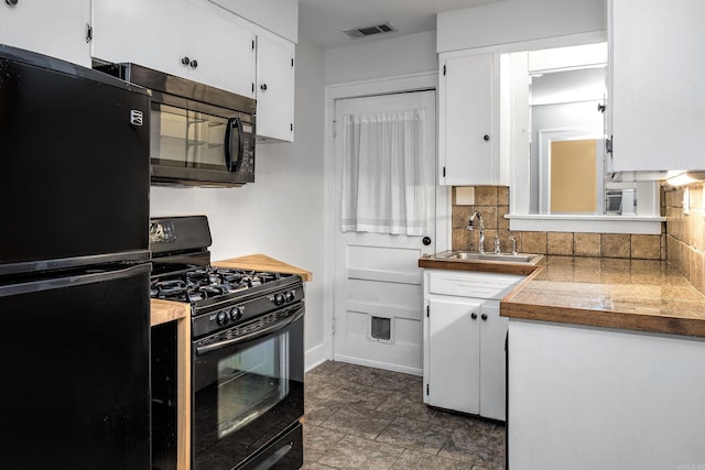 kitchen featuring a sink, visible vents, white cabinetry, backsplash, and black appliances