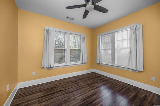 empty room featuring ceiling fan, dark wood-type flooring, visible vents, and baseboards