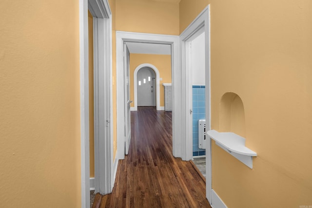 hallway with arched walkways and dark wood finished floors