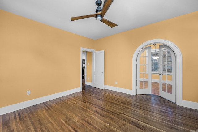 spare room with arched walkways, ceiling fan, dark wood-type flooring, baseboards, and french doors