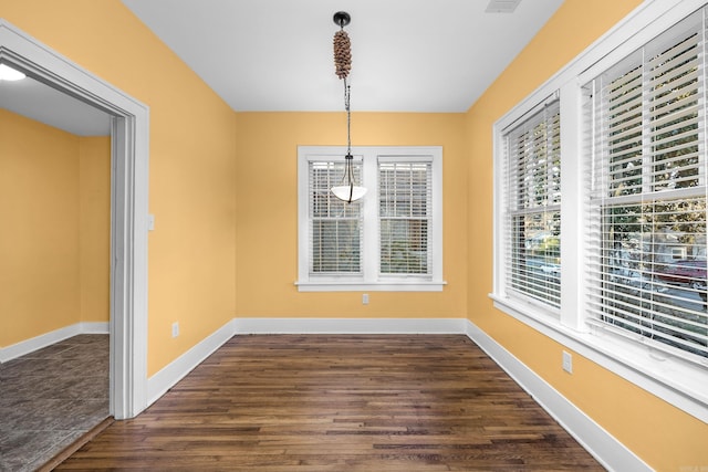 unfurnished dining area featuring dark wood-style flooring and baseboards