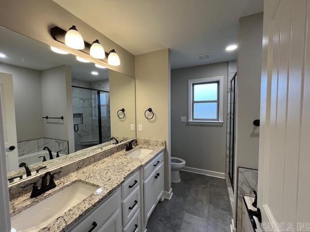 full bathroom featuring double vanity, a stall shower, a sink, and toilet