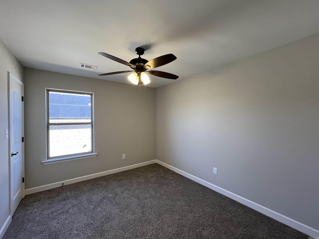 empty room with ceiling fan, dark colored carpet, visible vents, and baseboards