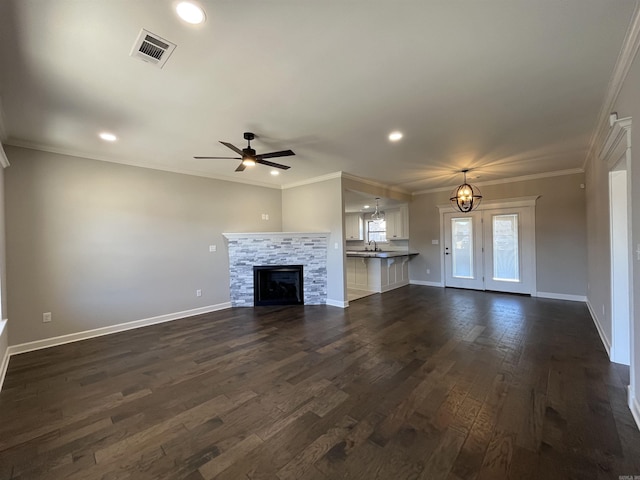 unfurnished living room with visible vents, baseboards, dark wood-style floors, ornamental molding, and a fireplace