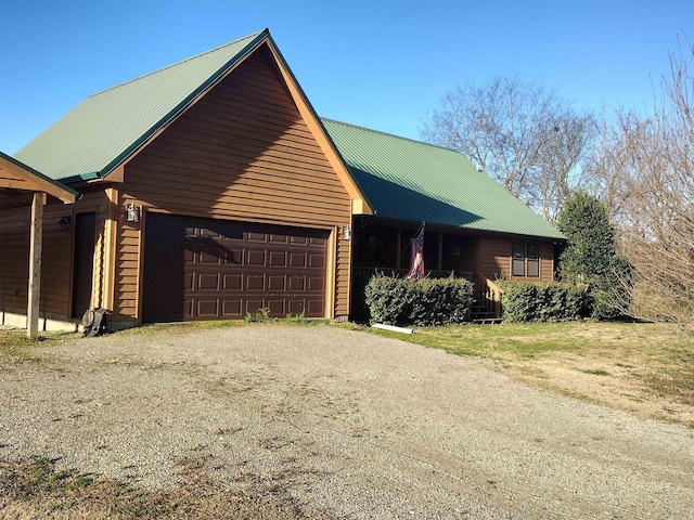 view of front of property featuring a garage, metal roof, and driveway