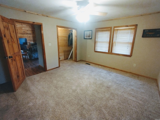 unfurnished bedroom featuring carpet, visible vents, ornamental molding, ceiling fan, and baseboards