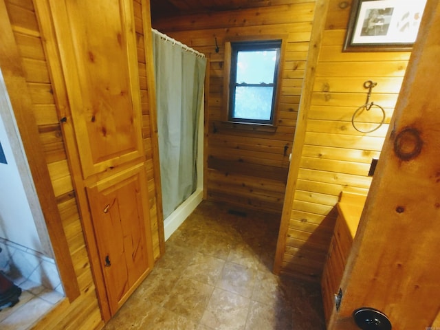 bathroom with curtained shower and wood walls