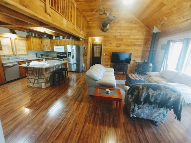 living area with a wood stove, wood walls, wood finished floors, high vaulted ceiling, and wooden ceiling