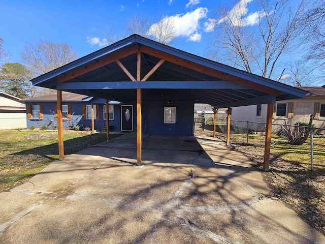 view of parking / parking lot with a carport, concrete driveway, and fence