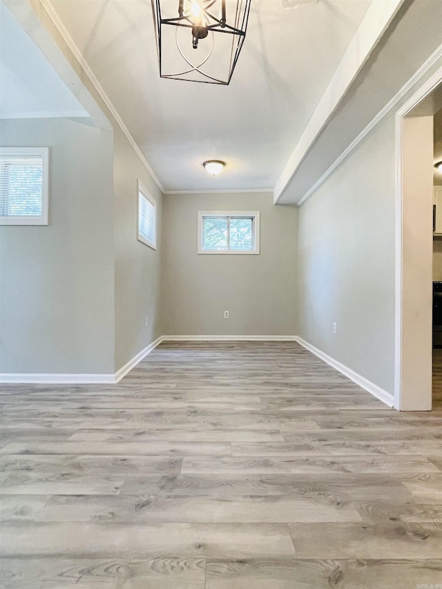 interior space with baseboards, a chandelier, wood finished floors, and crown molding