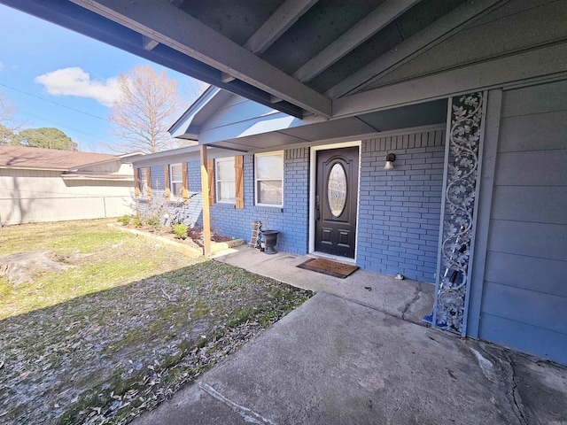 view of exterior entry with a yard and brick siding