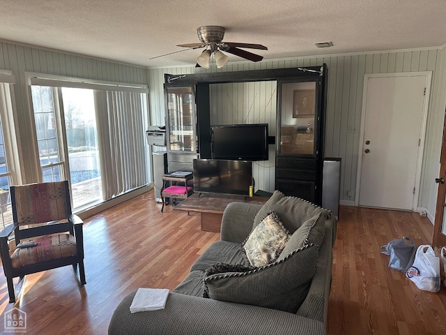 living room with a textured ceiling, ornamental molding, and wood finished floors