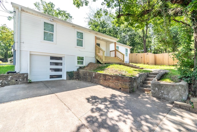 view of front of house with driveway, a garage, and fence