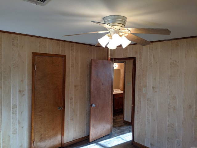 unfurnished room featuring ceiling fan, visible vents, and wooden walls