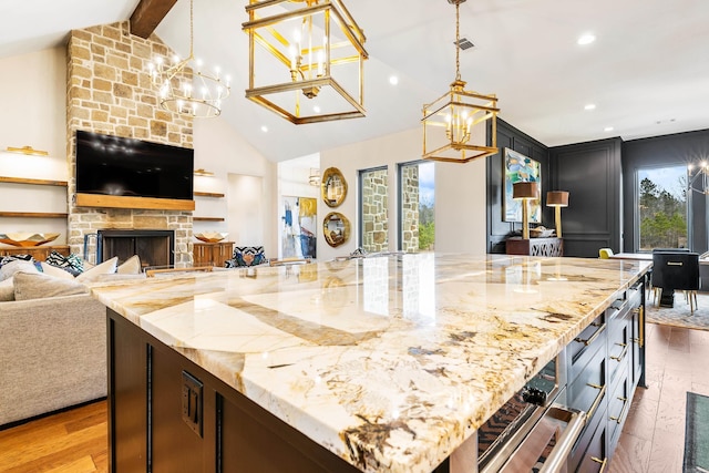 kitchen with a fireplace, beamed ceiling, hardwood / wood-style floors, and light stone countertops