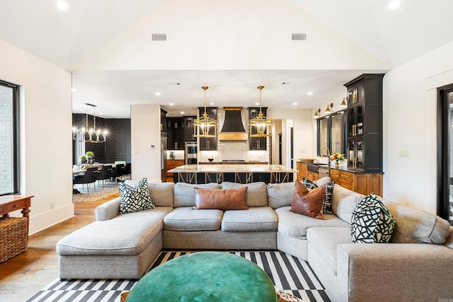 living room featuring light wood-style flooring, recessed lighting, visible vents, and an inviting chandelier