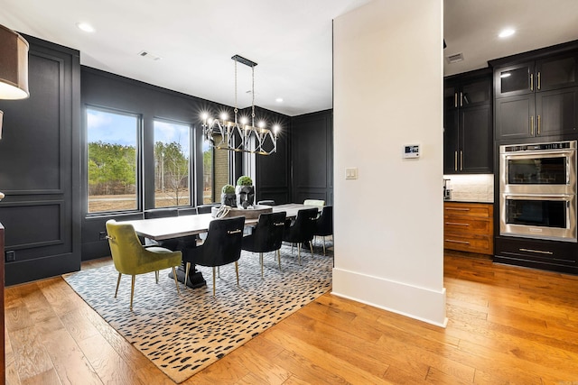 dining space with light wood-style floors, recessed lighting, visible vents, and an inviting chandelier