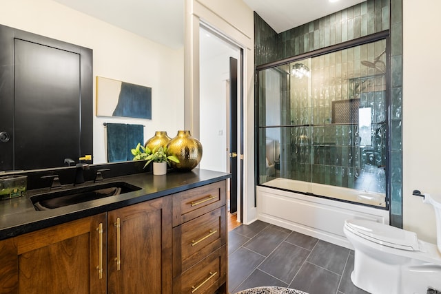 bathroom featuring toilet, bath / shower combo with glass door, and vanity