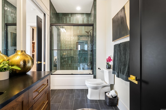 bathroom featuring toilet, shower / bath combination with glass door, and vanity