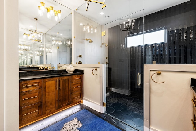 full bathroom featuring a notable chandelier, vanity, a shower stall, and tile patterned floors