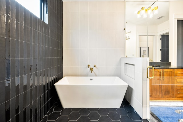 bathroom featuring a freestanding bath, visible vents, tile walls, and tile patterned floors