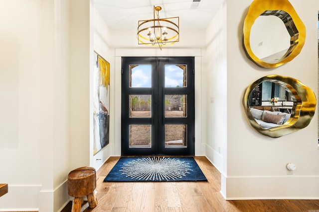 entrance foyer with wood finished floors, visible vents, baseboards, french doors, and an inviting chandelier