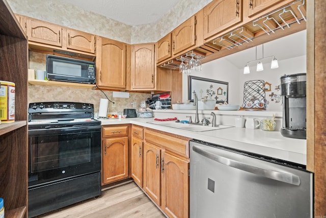 kitchen with light wood-style flooring, a sink, light countertops, backsplash, and black appliances