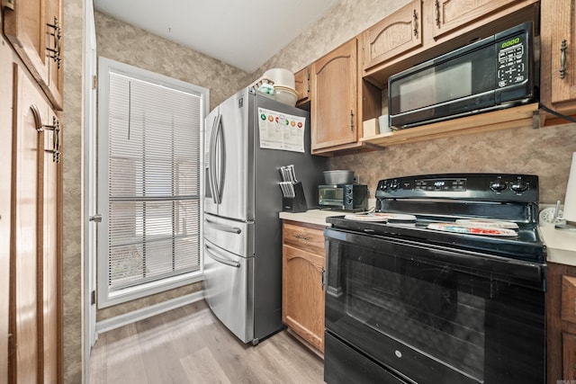 kitchen featuring light wood-type flooring, light countertops, and black appliances