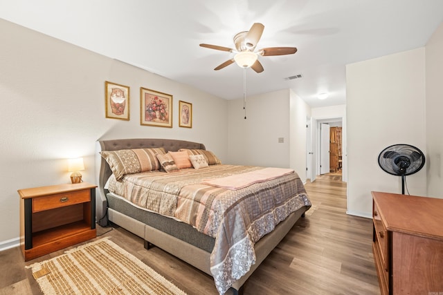 bedroom featuring visible vents, ceiling fan, baseboards, and wood finished floors