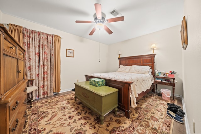 bedroom with ceiling fan, light wood finished floors, visible vents, and baseboards