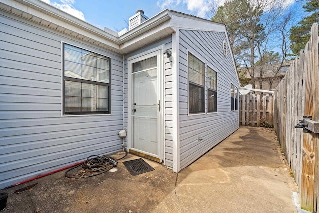 view of exterior entry with a patio area and fence