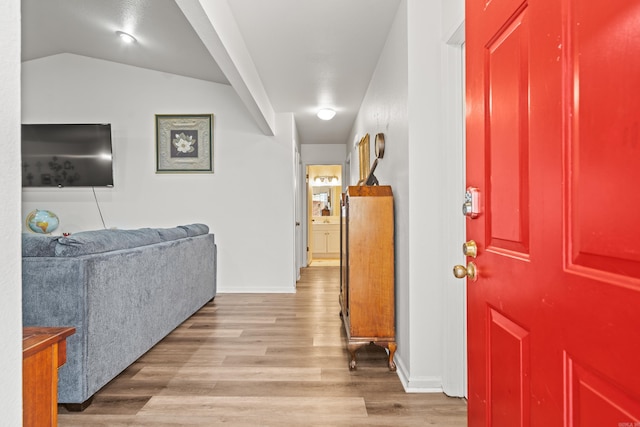 foyer entrance featuring baseboards, vaulted ceiling, and wood finished floors