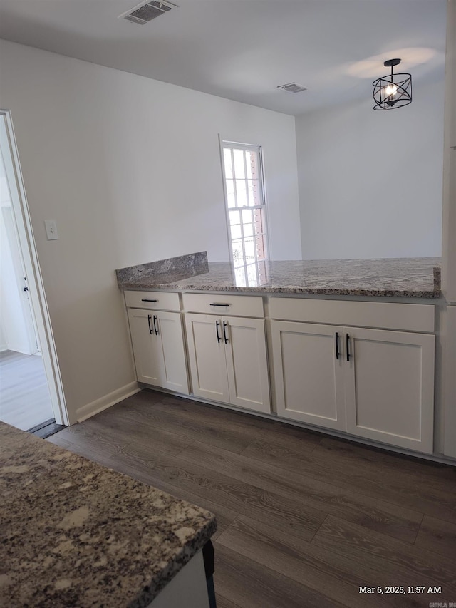 kitchen with visible vents, a peninsula, white cabinetry, and dark wood-type flooring