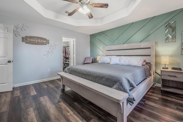 bedroom featuring wood finished floors, a raised ceiling, and baseboards