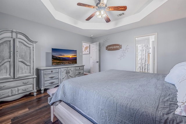 bedroom featuring dark wood-style floors, ceiling fan, a raised ceiling, and visible vents