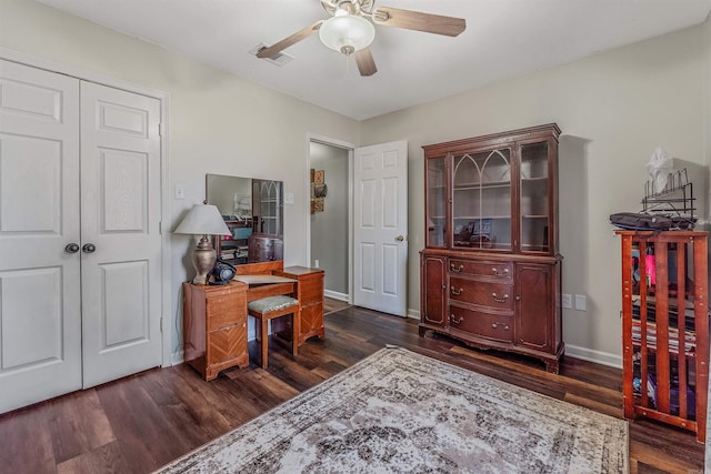 home office featuring baseboards, dark wood-style flooring, visible vents, and a ceiling fan