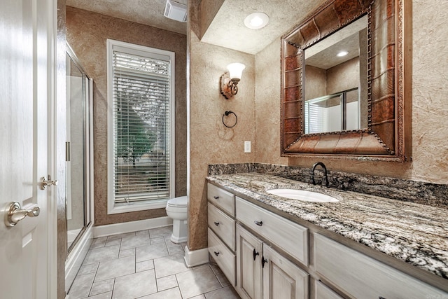 bathroom featuring toilet, a stall shower, vanity, a textured ceiling, and baseboards