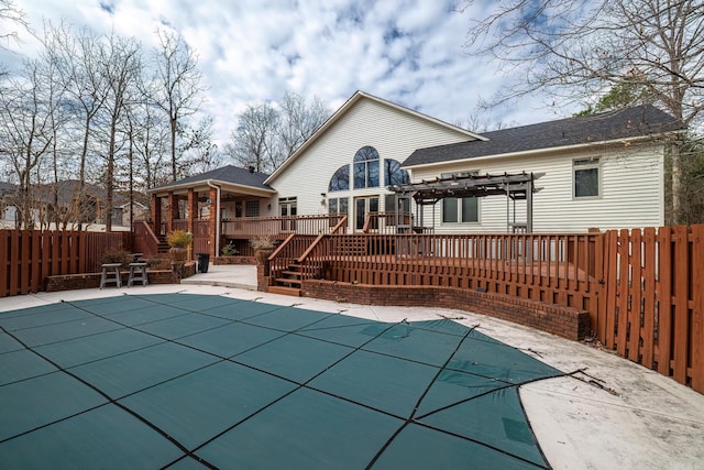 rear view of house with a patio, a fenced backyard, a wooden deck, a fenced in pool, and a pergola