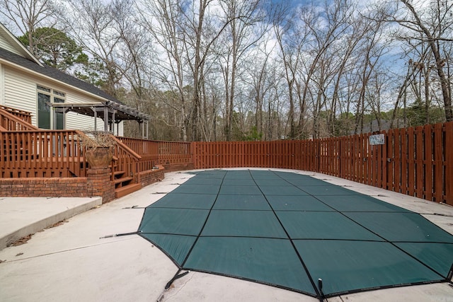 view of swimming pool with a fenced backyard, a wooden deck, a fenced in pool, a pergola, and a patio area