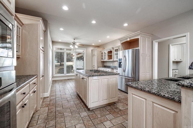 kitchen with recessed lighting, appliances with stainless steel finishes, glass insert cabinets, a kitchen island, and ceiling fan