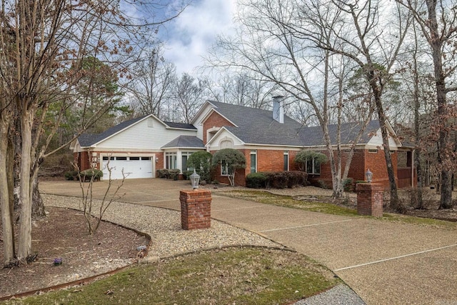 view of front facade with concrete driveway, a chimney, roof with shingles, an attached garage, and brick siding