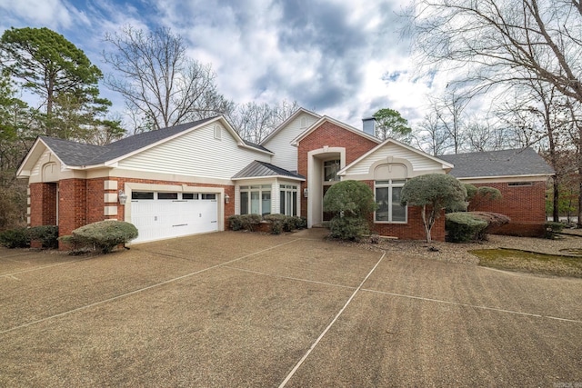 view of front of home with a garage, a chimney, concrete driveway, and brick siding