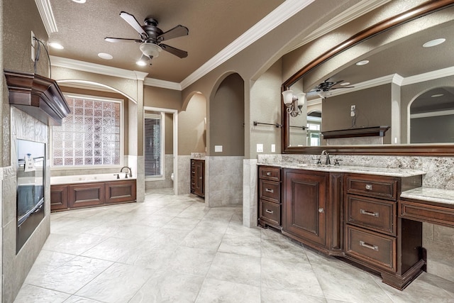 full bath with a bath, wainscoting, a ceiling fan, and tile walls