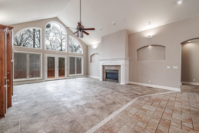 unfurnished living room featuring high vaulted ceiling, baseboards, a tiled fireplace, and a ceiling fan