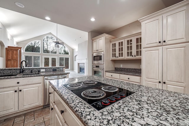 kitchen featuring ceiling fan, glass insert cabinets, vaulted ceiling, stainless steel appliances, and a sink