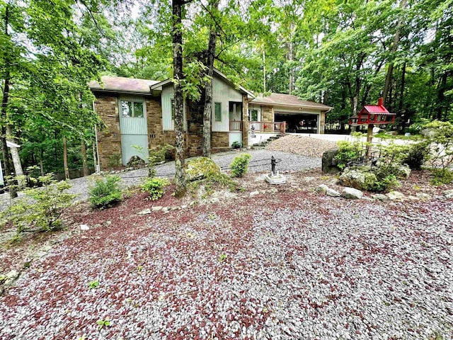 view of front of house featuring stone siding, an attached garage, and gravel driveway