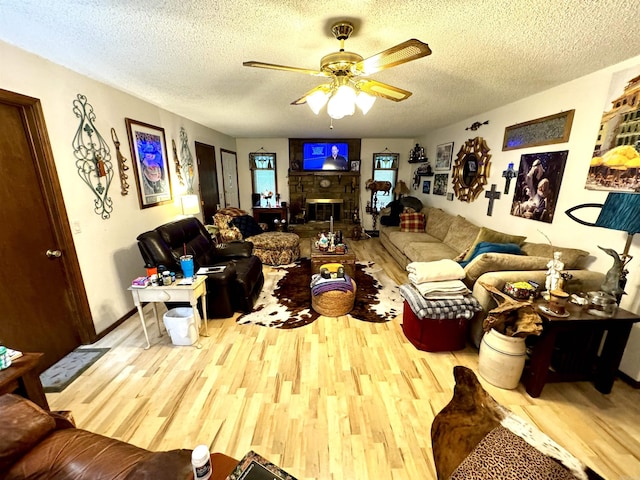 living room with ceiling fan, a fireplace, a textured ceiling, and wood finished floors