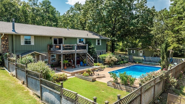 view of swimming pool featuring a fenced backyard, an outdoor structure, a yard, a wooden deck, and a patio area