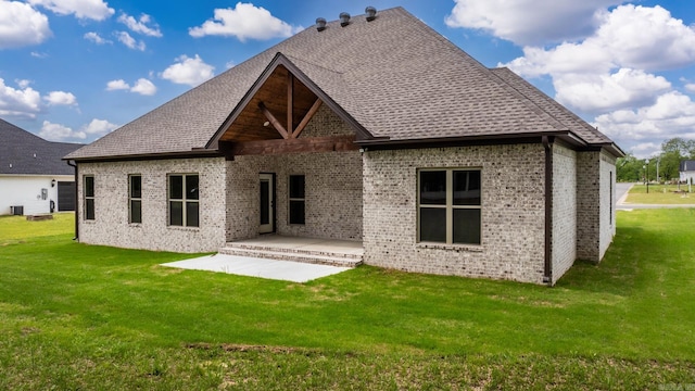 back of property featuring a lawn, roof with shingles, a patio area, and brick siding